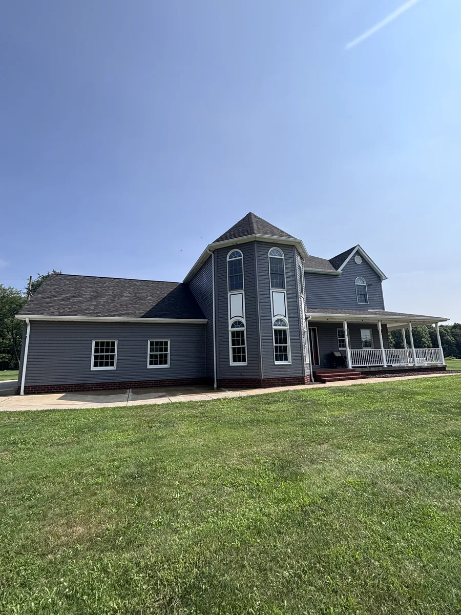 Gray two-story home with a wraparound porch after a full exterior wash
